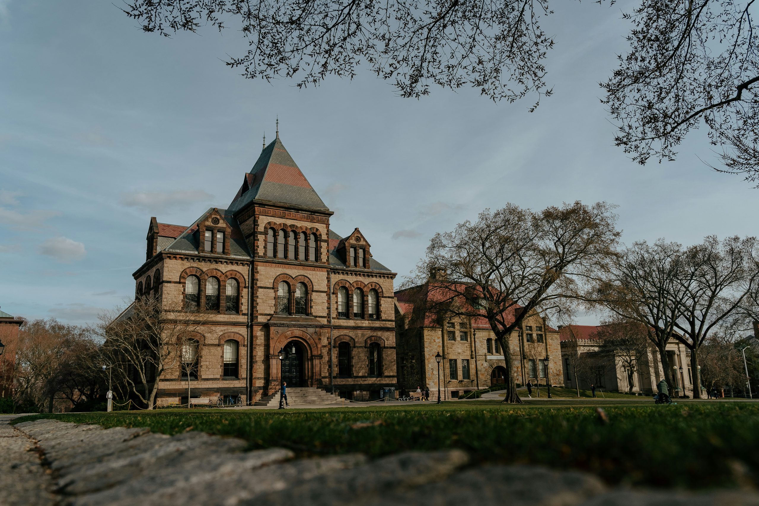 Sayles Hall at Brown University, with a stone facade, central tower, and trees bordering the campus lawn.