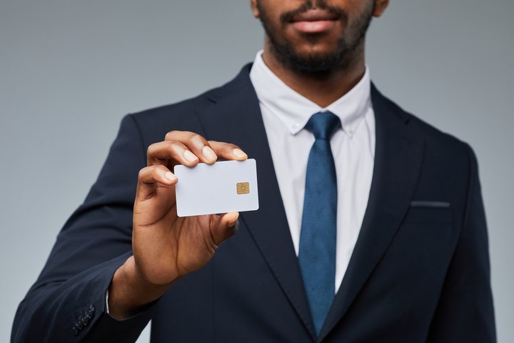 Close up of businessman holding blank business credit cards personally guaranteed mockup and showing to camera, copy space